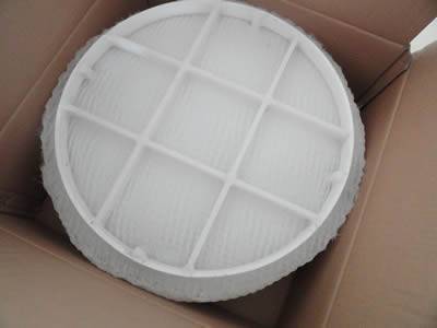 帶有網格的圓形白色聚丙烯除霧器墊在開口紙箱中。