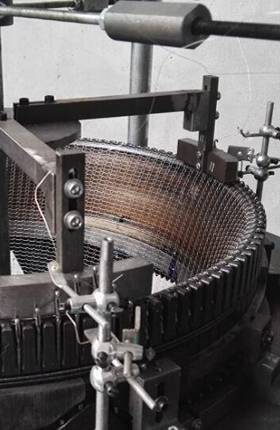 A knitting machine is producing knitted mesh.