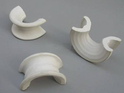 Three ceramic Intalox Saddle ring on the gray background.