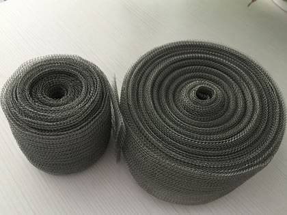 Deux rouleaux de mailles en fil de fer tricoté aplaties sur fond gris.