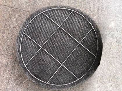 A ginning knitted wire mesh demister pad on the ground.