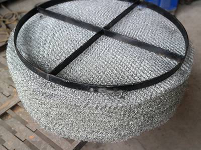 A stainless steel demister pad with carbon steel support grating.